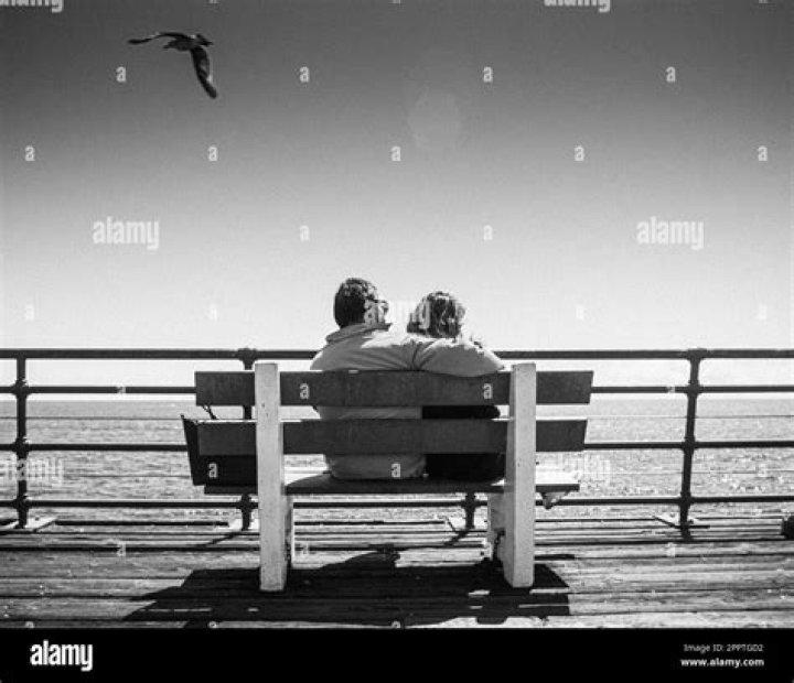 a man and woman sitting next to each other holding coffee cups